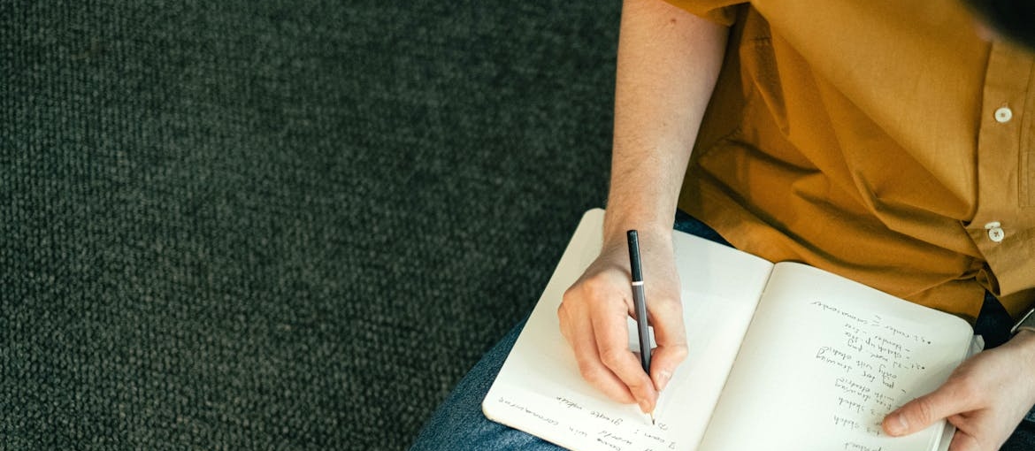 Woman writing about social isolation after leaving rehab in her notebook.