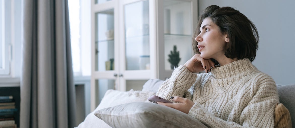 Woman looking out of her window and thinking about starting digital minimalism in recovery.