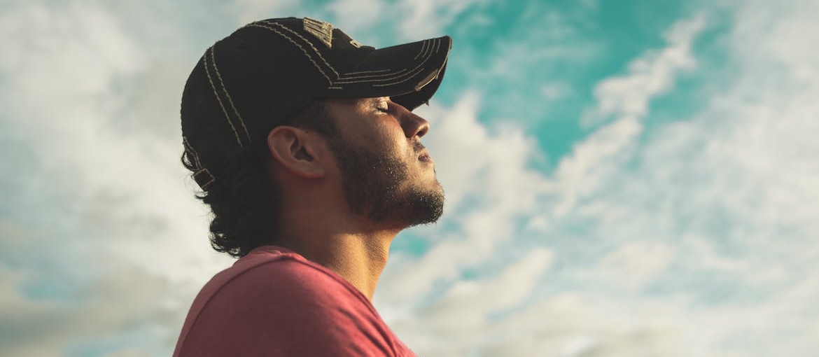 Man with closed eyes looking up at the sky.