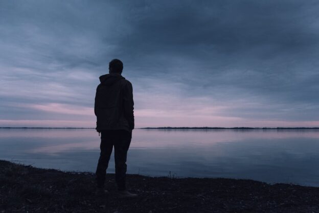 Man looking at the sea while experiencing social isolation after leaving rehab.