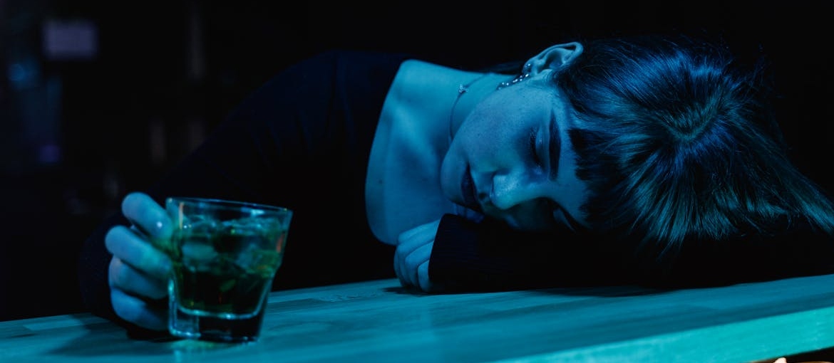 Woman lying on a bar and holding an alcoholic drink.