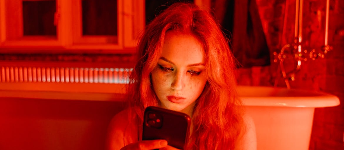 Woman crying while looking at her phone and researching digital minimalism in recovery.