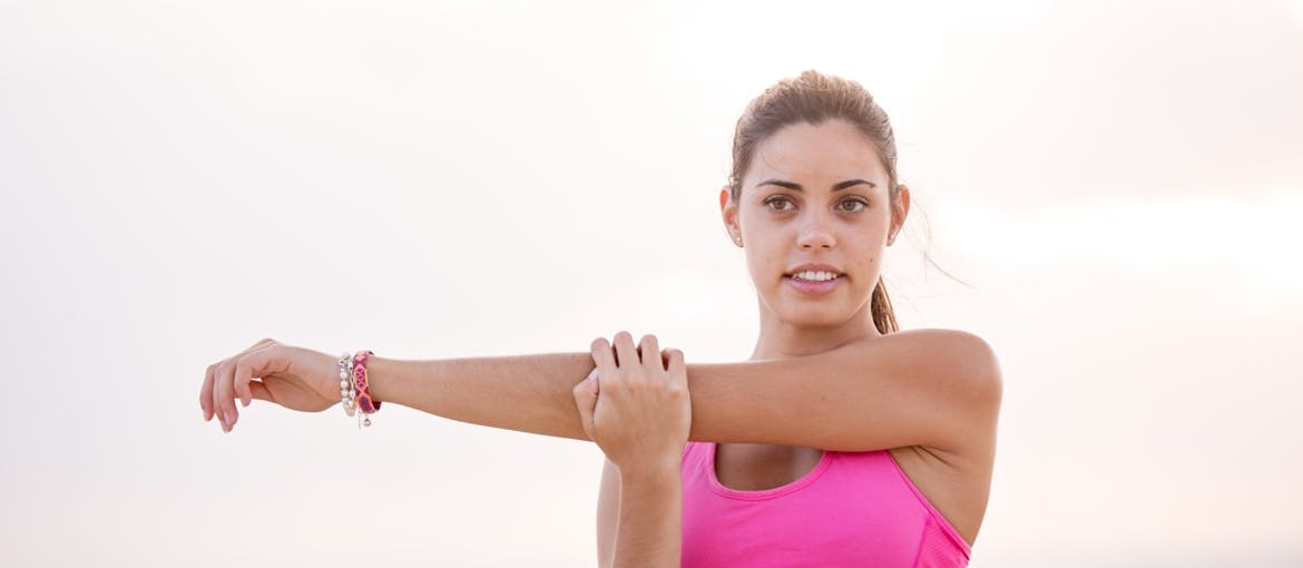 Woman in a pink top stretching her arms.