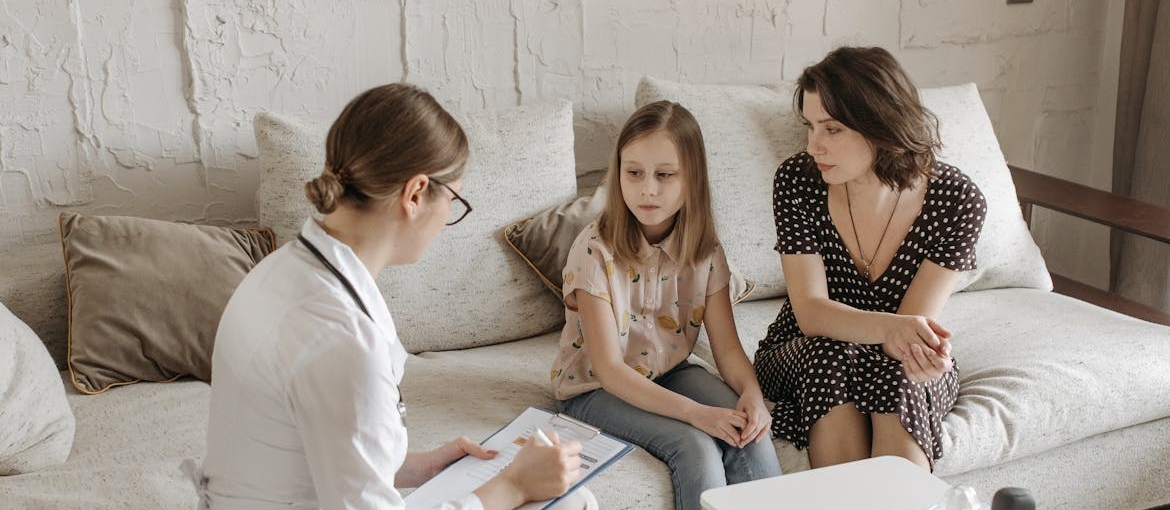 Therapist and mother having a conversation with a young child about addiction and recovery.
