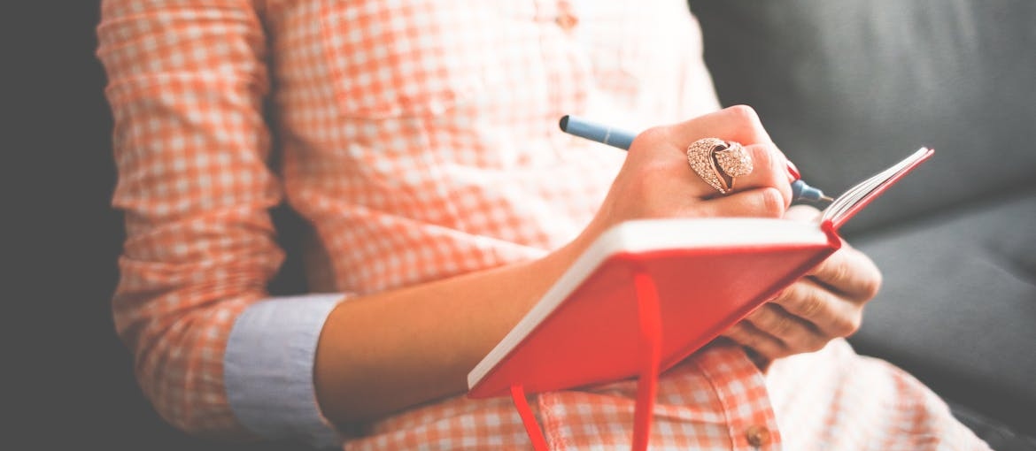 Woman sitting on the couch and journaling.
