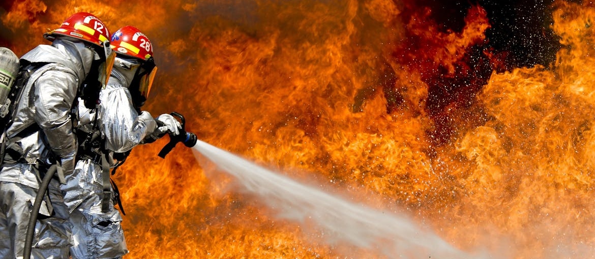 Two firefighters putting out a fire.