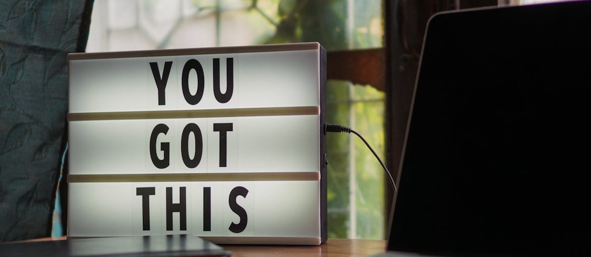 Motivational sign next to a laptop.
