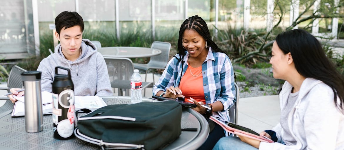 Three college students sitting around a table and laughing.