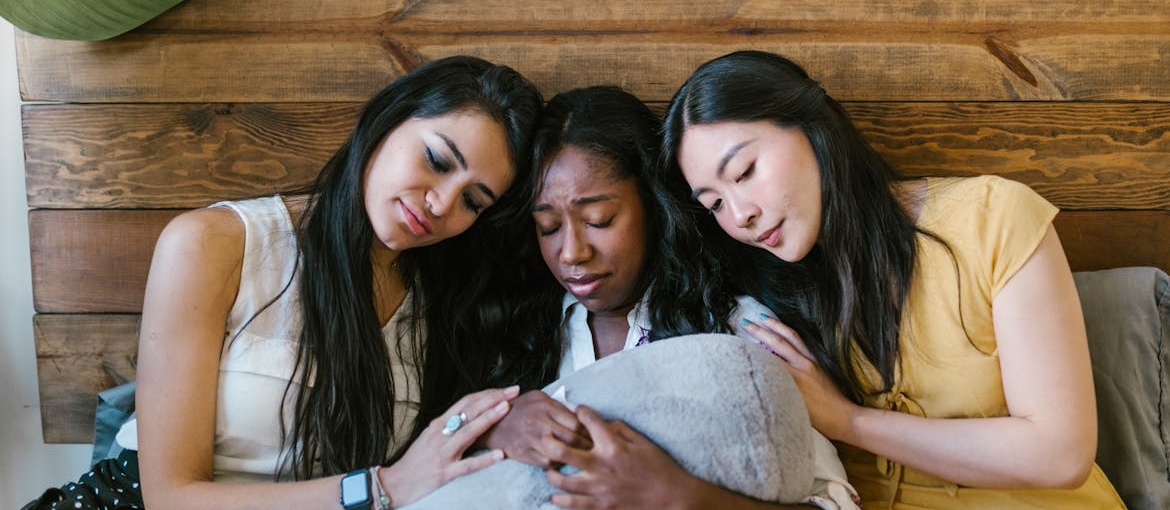 Two girls comforting a crying friend.