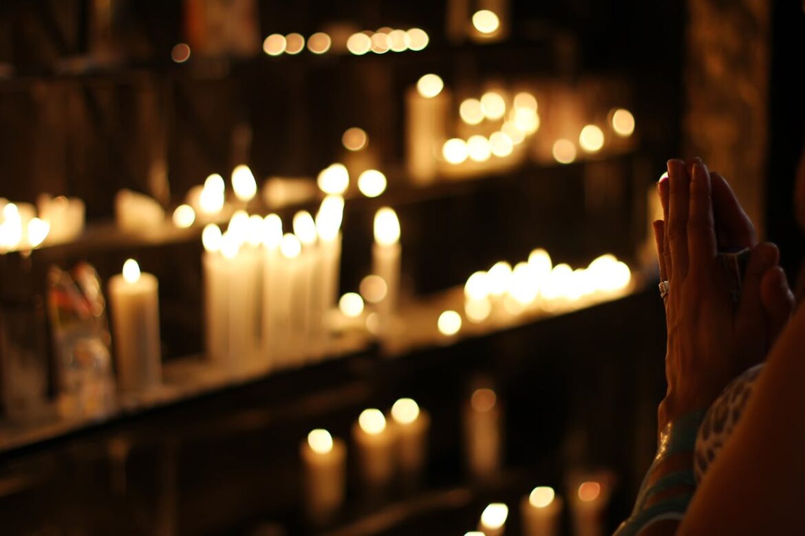 Woman praying in front of candles.