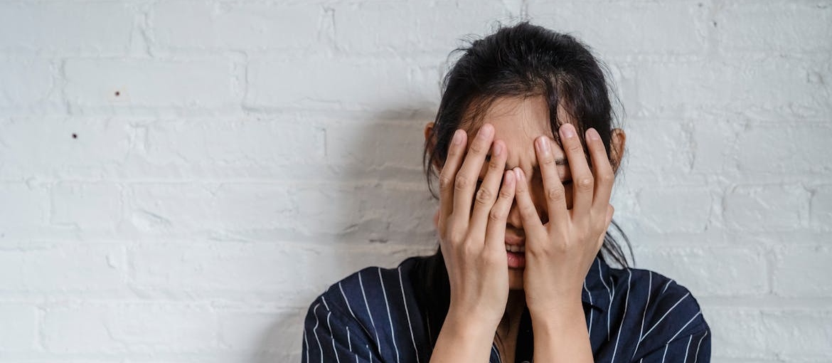 Woman covering her face while worrying about being neurodivergent addiction recovery.