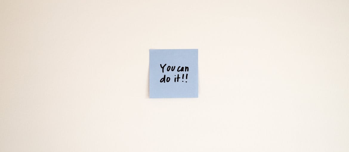 Positive affirmations for recovering addicts written on a blue post it note.
