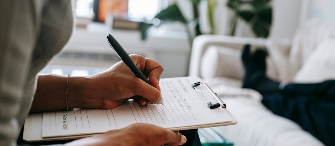 Woman writing on a clipboard while talking to a patient.
