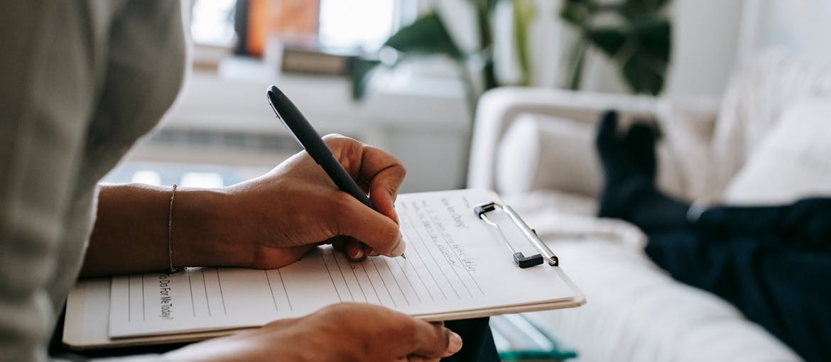 Woman writing in a clipboard while talking to a patient.