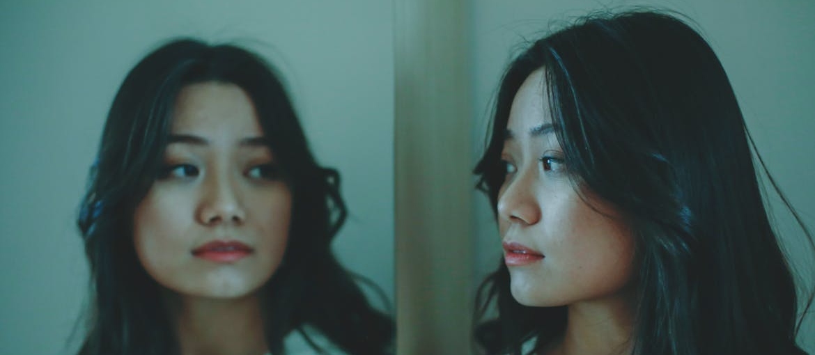 Sad woman looking at herself in the mirror.