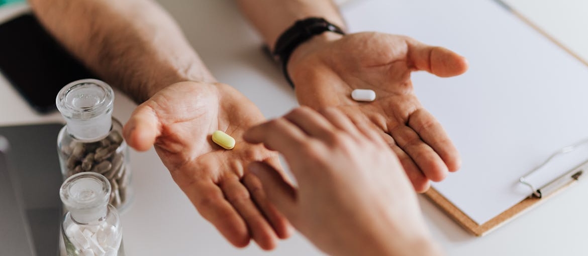 Doctor offering two pills to a patient.