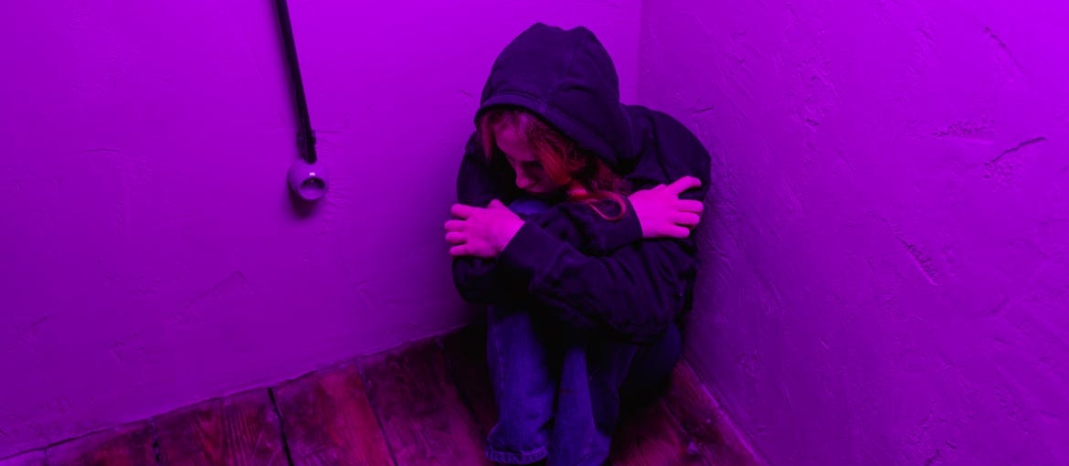 Woman sitting in the corner of a room struggling with cocaine and depression.