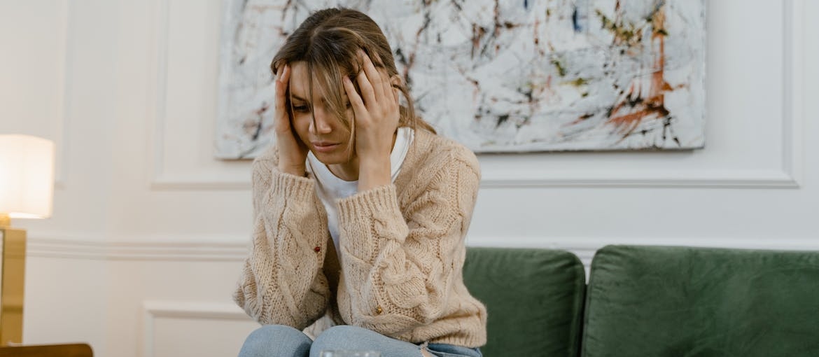 Woman holding her head in pain while struggling with benzos and alcohol use.