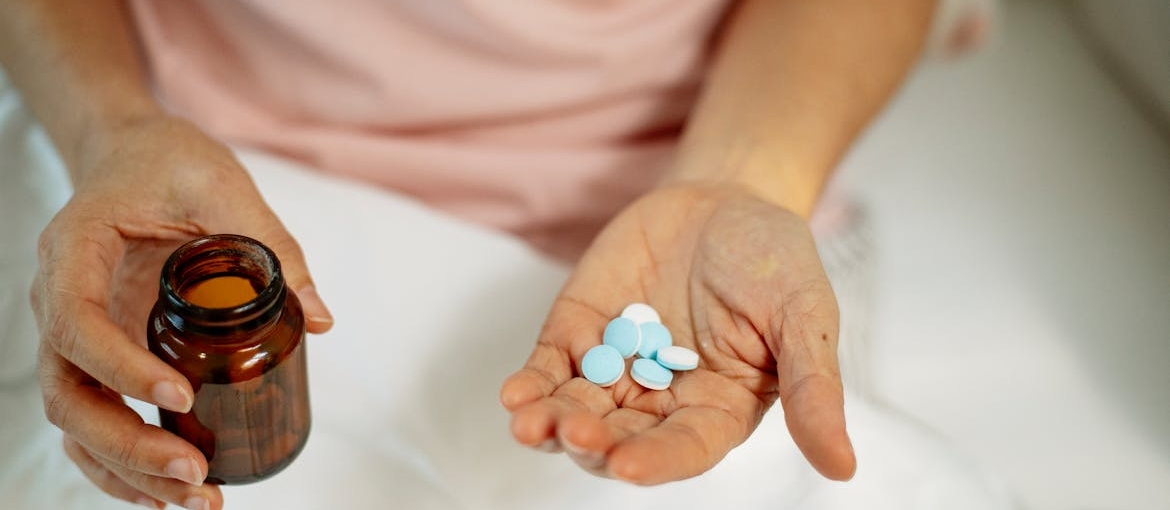 Person holding a bottle of pills and pills in their hand.