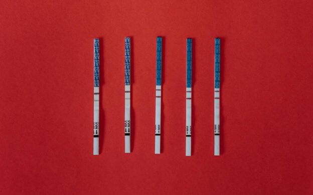 Five fentanyl test strips on a red background.