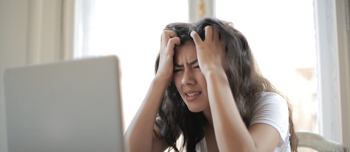 Woman struggling with LSD and bipolar disorder scratching her head in agitation.
