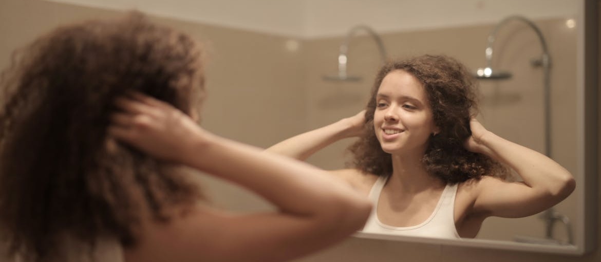 Woman saying positive affirmations for recovering addicts to herself in the mirror.