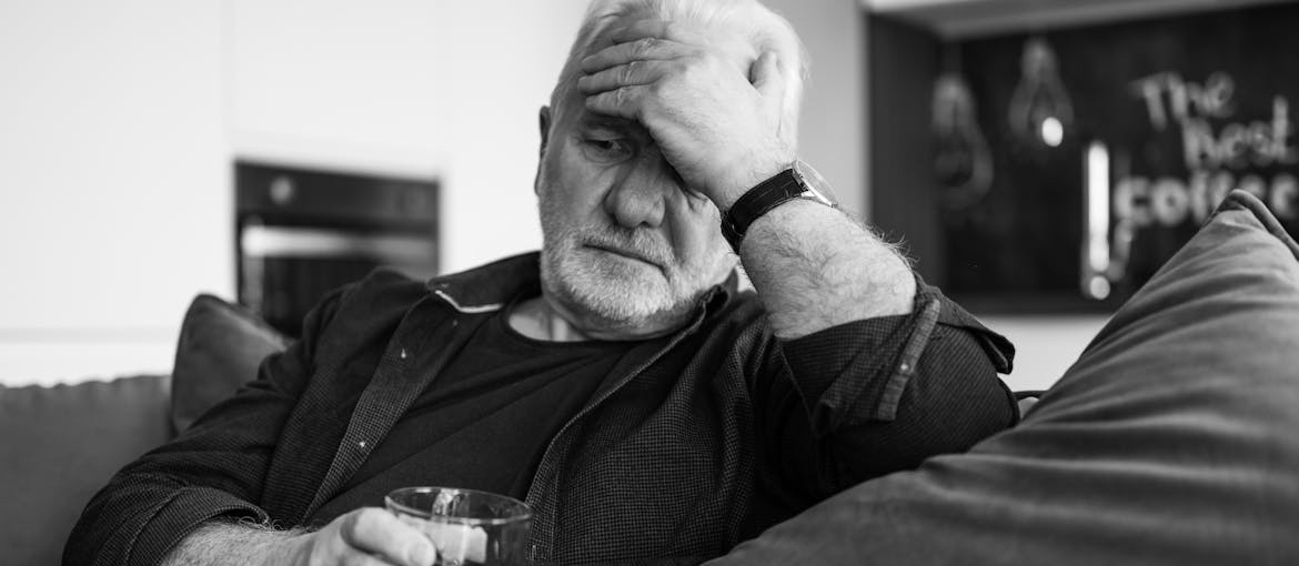 Man sitting on the couch and drinking alcohol.