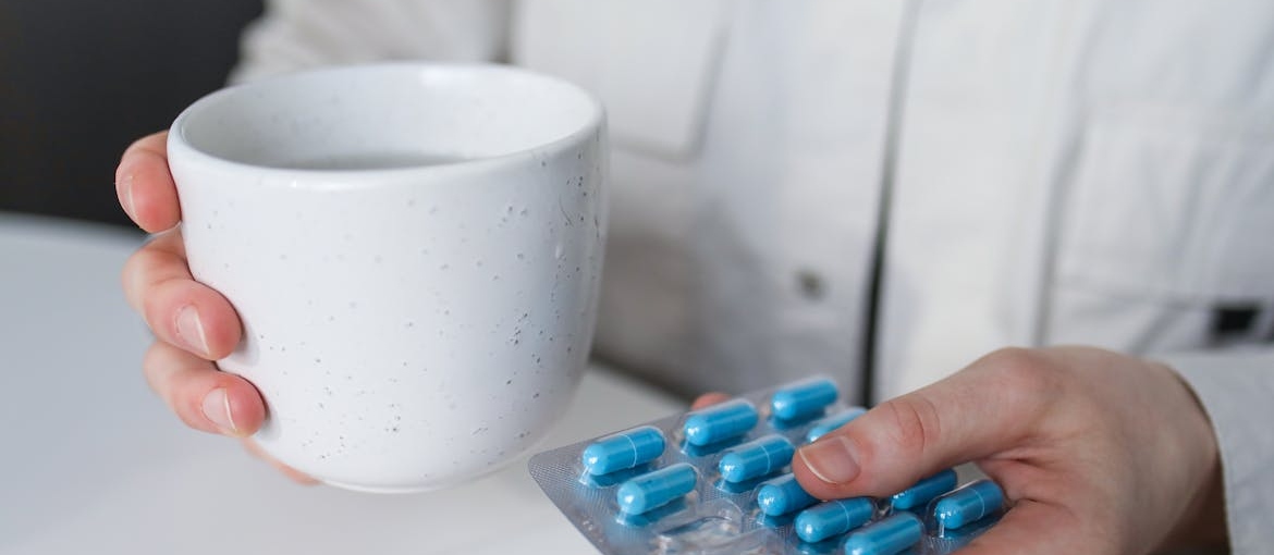 Doctor holding a glass of water and a blister of pills.