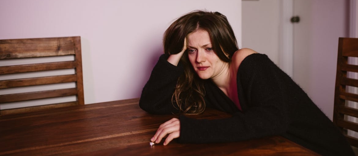 Woman sitting at a table and crying.