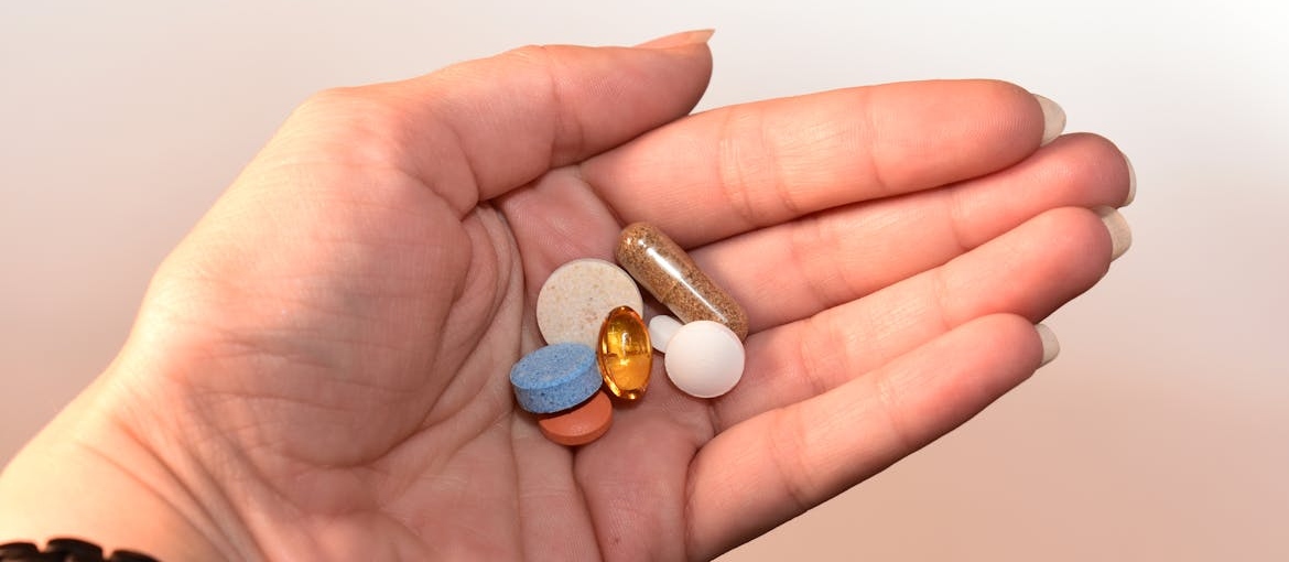 Person holding vitamin pills in their hand.