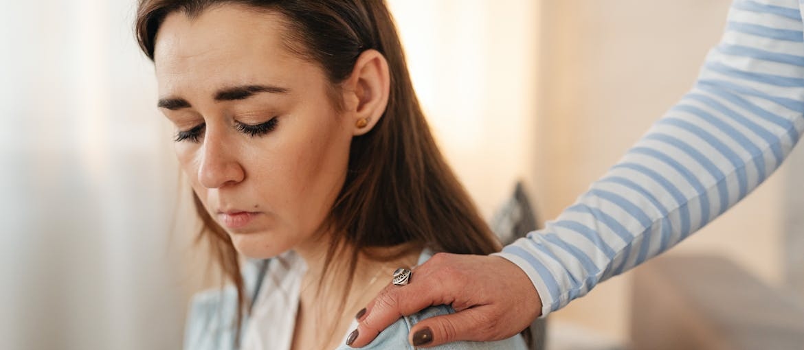 Woman putting her hand on a friend's shoulder.