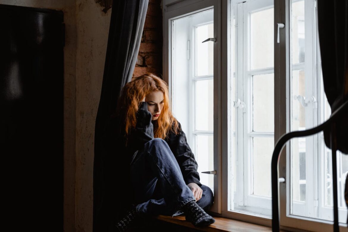 Sad woman sitting by the window.