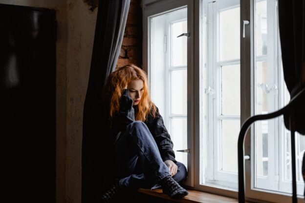 Sad woman sitting by the window.