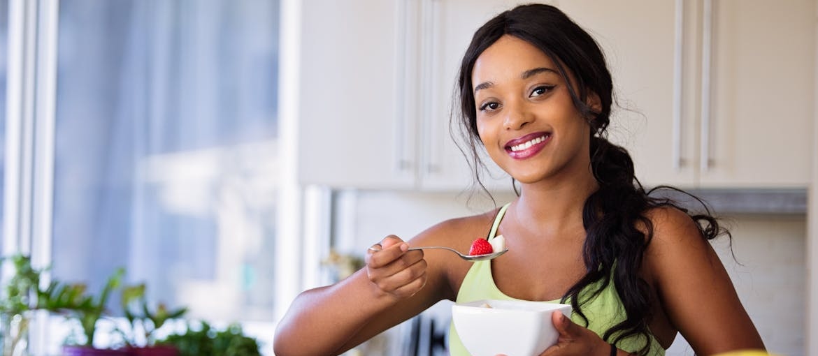 Woman eating a fruit salad in her kitchen.