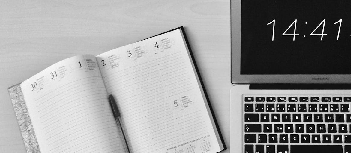 Open planner next to a laptop.