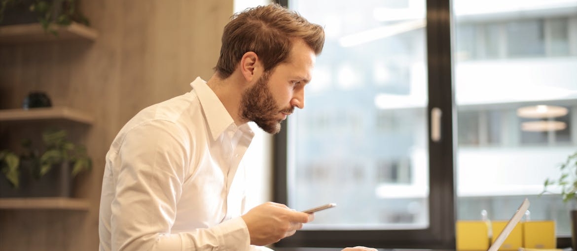 Man working on a laptop and making a phone call.