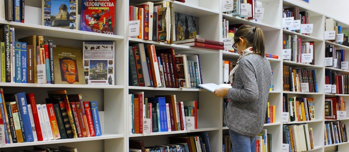 Woman looking for best stress management books in a library.