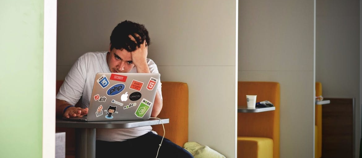 Man sitting at a booth and working on his laptop.