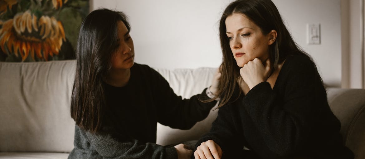 Woman comforting a crying woman while talking about Klonopin and alcohol addiction treatment.