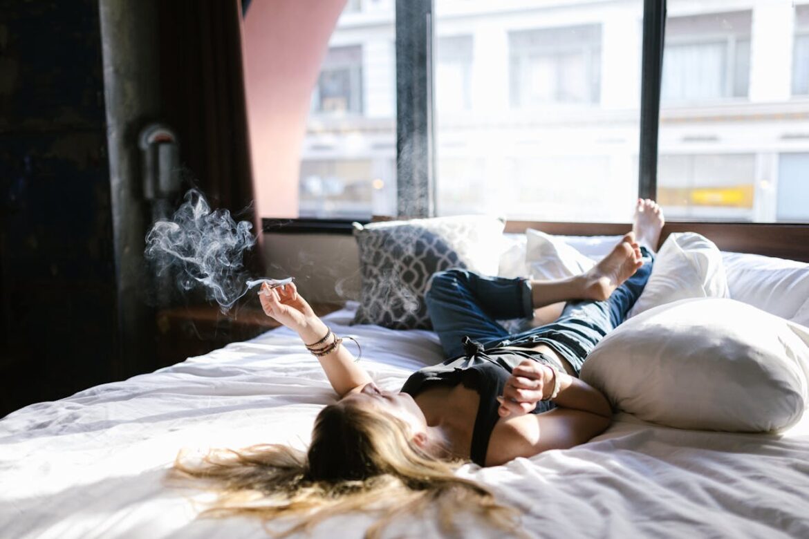 Woman lying in bed and smoking marijuana.