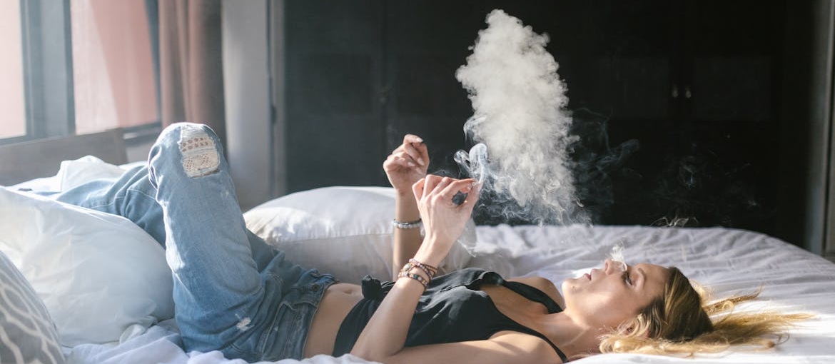 Woman smoking marijuana in bed.