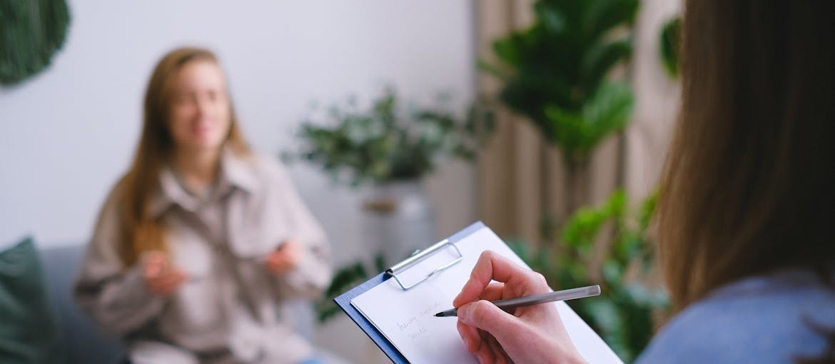 Therapist explaining the stages of relapse to her patient while writing in a clipboard.