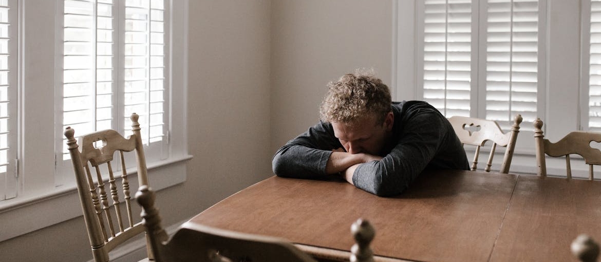 Depressed man leaning on a dining table.