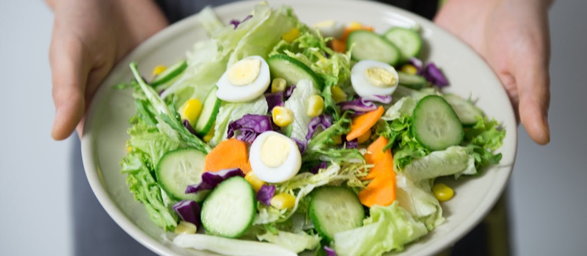 Person holding a bowl of salad.