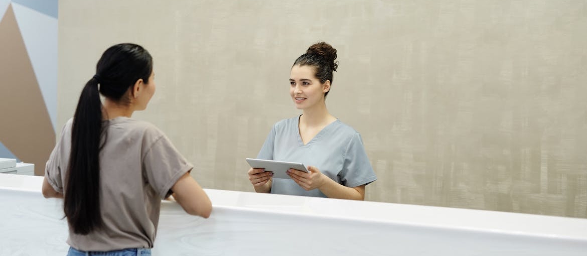Woman talking to a receptionist at a rehab clinic.