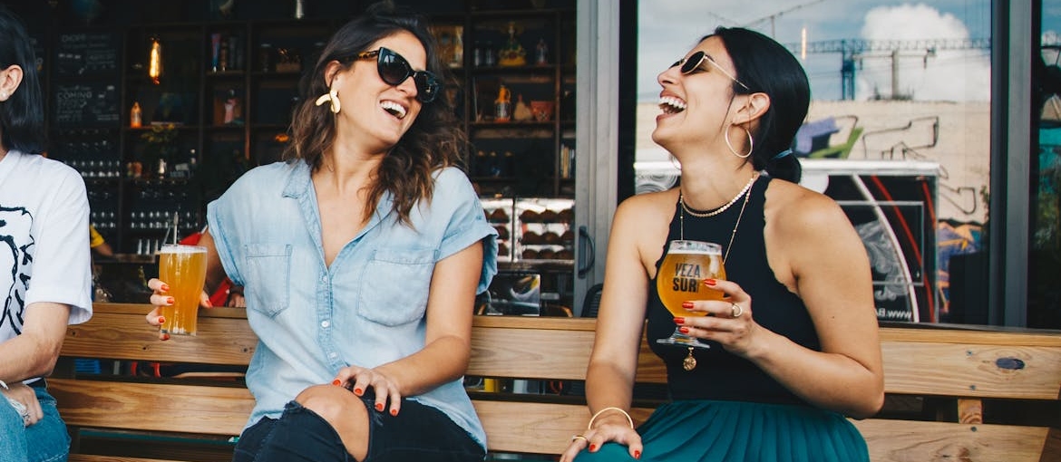 Women drinking beer and laughing with each other.