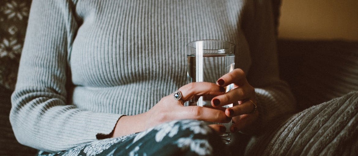 Woman holding a glass of water.