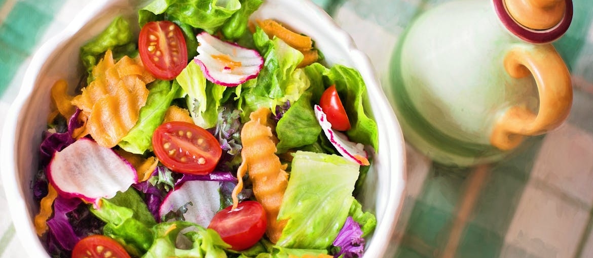 Salad dressing next to a bowl of salad, one of the best foods for detoxing from drugs.