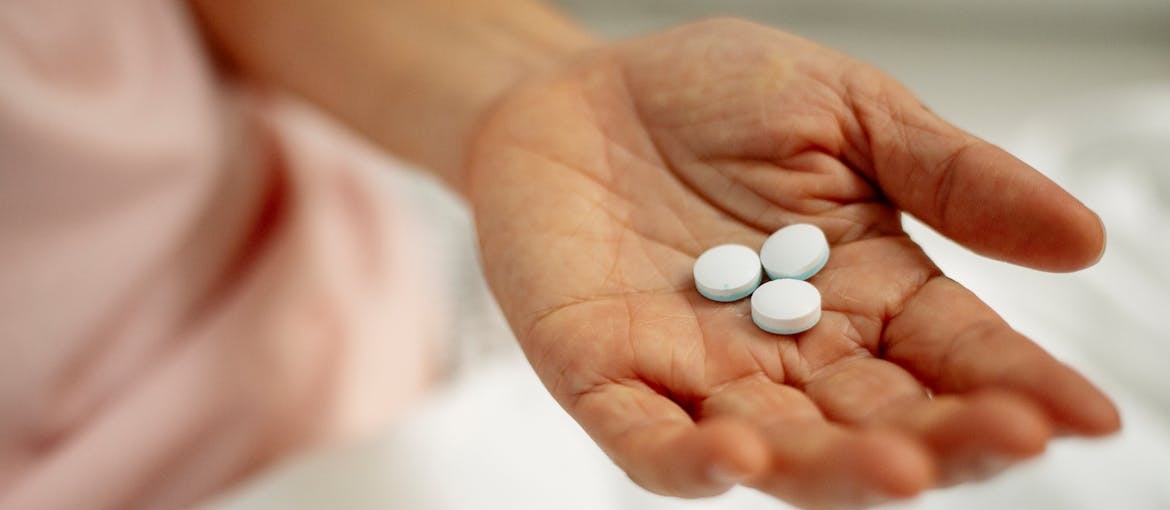 Person holding pills in their hand while going through OCD and addiction treatment.