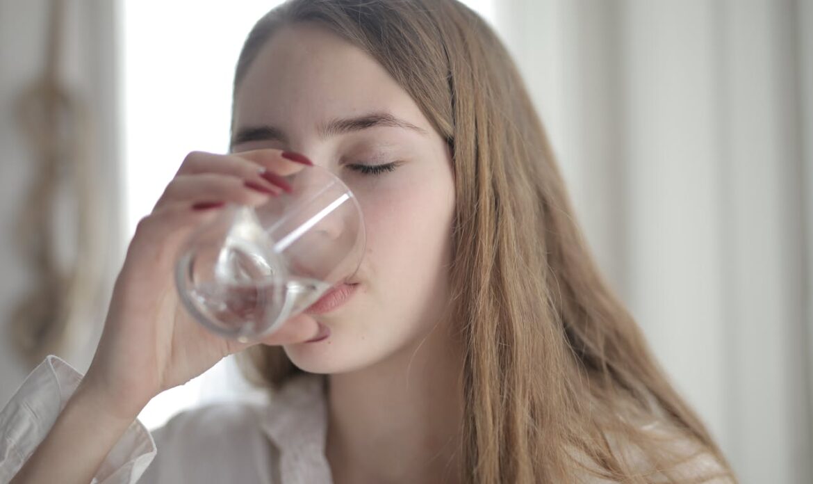 Woman drinking a glass of water after learning how to get weed out of your system.